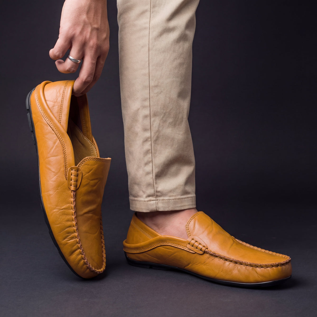 Men's Slip-On Loafers with Apron Stitching in Saddle – worn and held front view | Hensley London