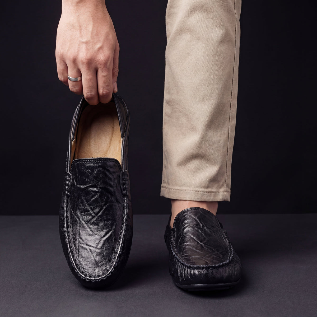 Men's Slip-On Loafers with Apron Stitching in Black – worn and held front view | Hensley London