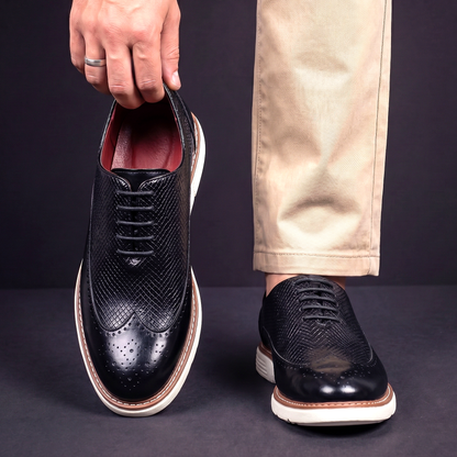 Men's Faux Leather Textured Wingtip Brogue Shoes in Black – worn and held front view | Hensley London