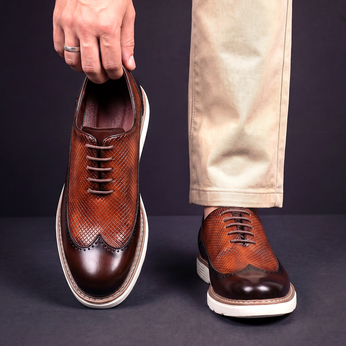 Men's Faux Leather Textured Wingtip Brogue Shoes in Brown – worn and held front view | Hensley London