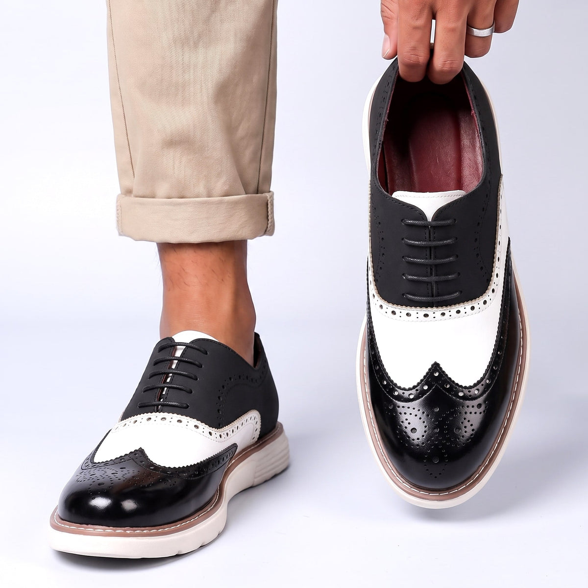 Men's Faux Leather Two-Tone Wingtip Brogue Shoes in Black – worn and held front view | Hensley London