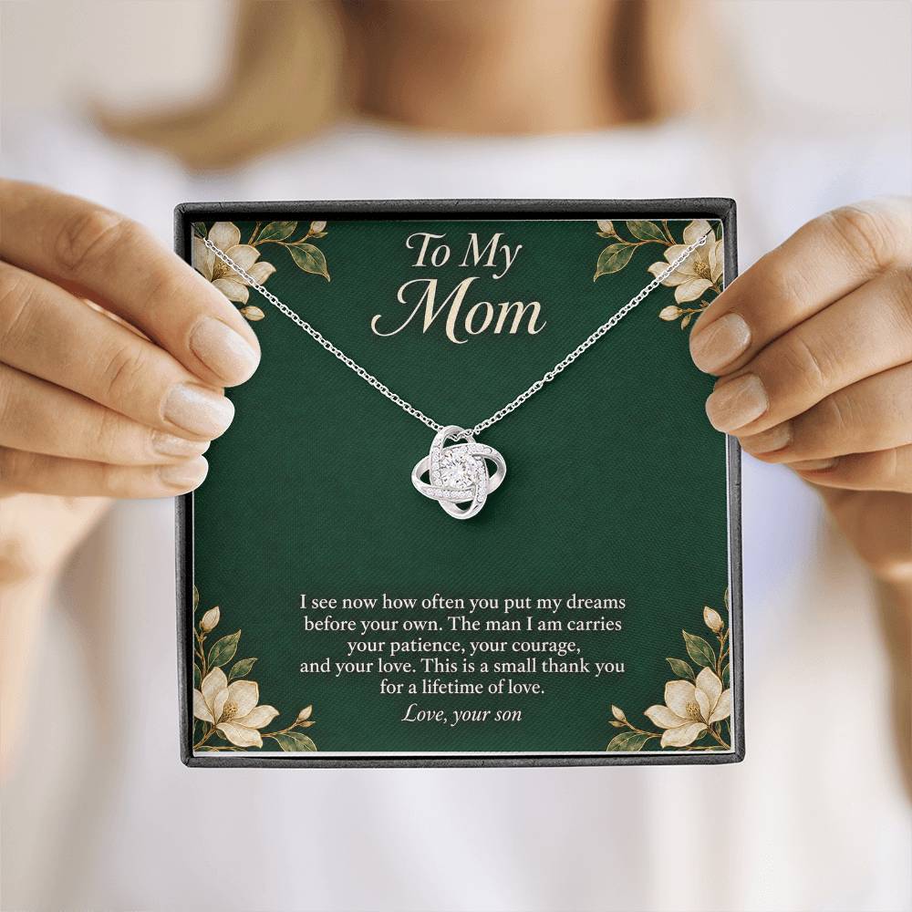 White-gold Love Knot necklace and emerald Mom message card held upright | Hensley London