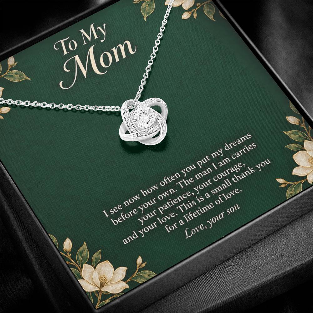 White-gold Love Knot necklace and emerald Mom message card in standard box, close angled view | Hensley London