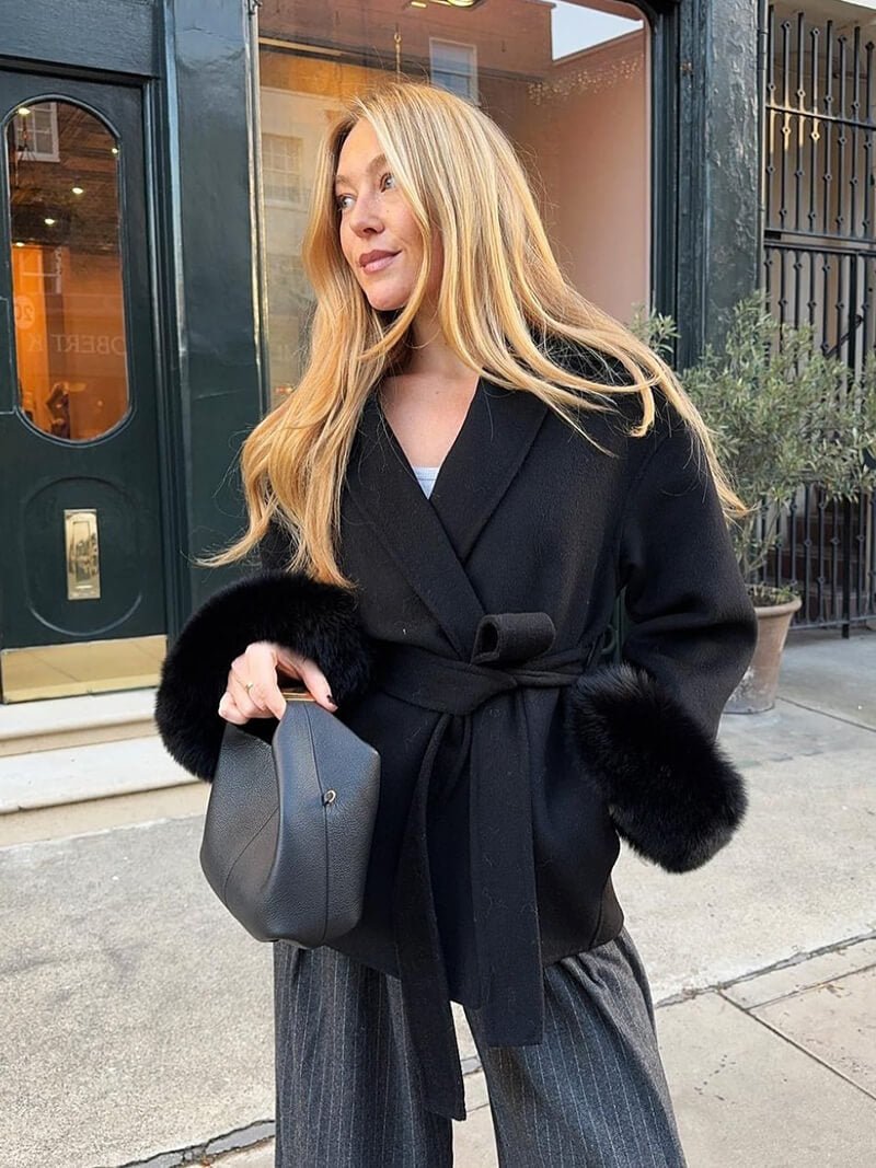 Women's Belted Shawl-Collar Coat with Textured Cuffs in Black – front outdoor worn view | Hensley London