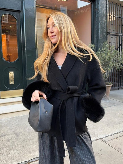 Women's Belted Shawl-Collar Coat with Textured Cuffs in Black – front outdoor worn view | Hensley London
